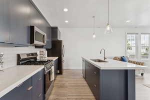 Kitchen with stainless steel appliances, pendant lighting, modern cabinets, light wood-style flooring, and a breakfast bar area