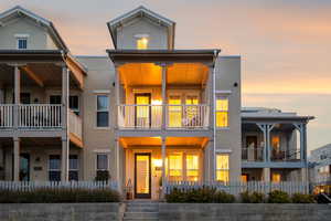 Back of house at dusk featuring stucco siding, a fenced front yard, and a porch