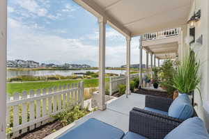 Covered porch featuring a water view