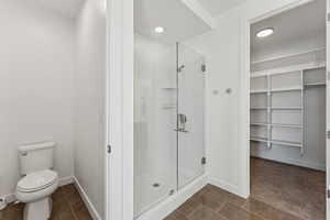 Bathroom featuring a stall shower, dark tile patterned floors, a walk in closet, and recessed lighting