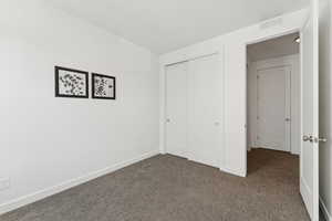 Unfurnished bedroom with dark carpet and a closet