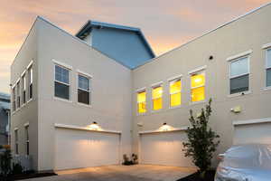 View of front of property featuring stucco siding, an attached garage, and driveway