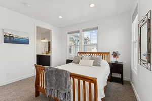 Bedroom with dark colored carpet, ensuite bathroom, and recessed lighting