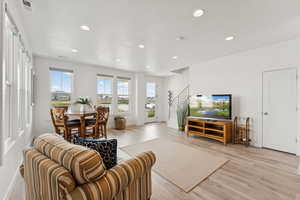 Living room with stairs, recessed lighting, and light wood-style flooring