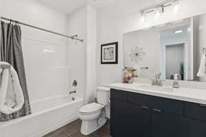 Bathroom with shower / tub combo, vanity, and dark tile patterned flooring