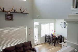 Living area featuring light wood-style floors, a high ceiling, and healthy amount of natural light