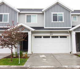 Traditional-style house featuring board and batten siding, an attached garage, driveway, and roof with shingles