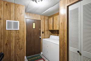 Washroom with wooden walls, cabinet space, and separate washer and dryer
