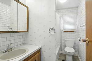 Full bathroom featuring shower / tub combo, vanity, wood finished floors, decorative backsplash, and tile walls