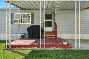Doorway to property featuring a lawn and a deck