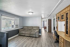 Living area featuring an office area, light wood-style floors, and a textured ceiling