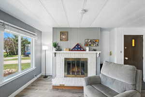 Living room featuring wood walls, wood finished floors, a fireplace, and a textured ceiling