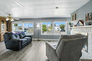Living room featuring a fireplace, light wood-type flooring, a textured ceiling, and wood walls