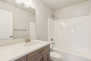 Full bathroom featuring bathtub / shower combination, vanity, and a textured ceiling