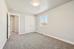 Unfurnished bedroom with a textured ceiling, carpet, and a closet