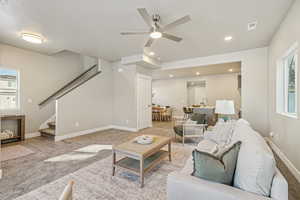 Carpeted living room with stairs, ceiling fan, and a textured ceiling