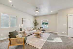 Living room featuring a textured ceiling, light carpet, recessed lighting, and ceiling fan