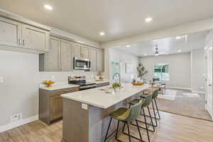 Kitchen featuring stainless steel appliances, open floor plan, a kitchen bar, recessed lighting, and light wood-type flooring