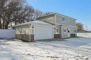 View of front facade with stone siding, an attached garage, and board and batten siding