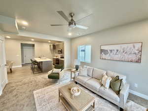 Living area with light carpet, ceiling fan, and recessed lighting