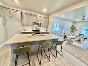 Kitchen featuring recessed lighting, a breakfast bar area, stainless steel appliances, a kitchen island with sink, and light stone countertops
