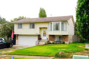 Bi-level home with brick siding, driveway, and a garage