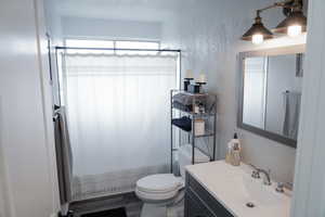 Full bath with vanity and a textured wall