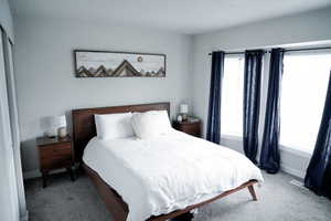 Carpeted bedroom featuring baseboards and a textured ceiling