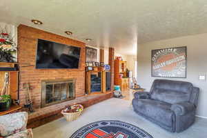 Living area featuring carpet flooring, a fireplace, and a textured ceiling
