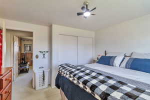 Bedroom featuring light colored carpet, a closet, and ceiling fan