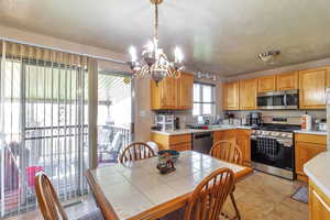 Kitchen with light countertops, stainless steel appliances, decorative light fixtures, a textured ceiling, and a chandelier