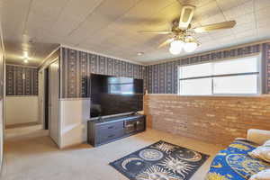 Living area featuring carpet floors, wallpapered walls, ceiling fan, and wainscoting
