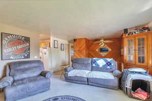 Living room featuring wood walls, light carpet, and a textured ceiling