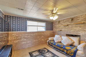 Carpeted bedroom with brick wall and ceiling fan