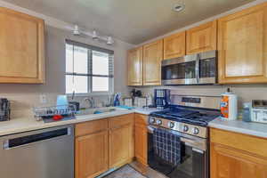 Kitchen with appliances with stainless steel finishes, a textured ceiling, and light countertops