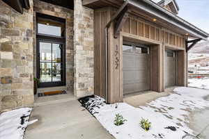 Snow covered property entrance featuring stone siding and board and batten siding
