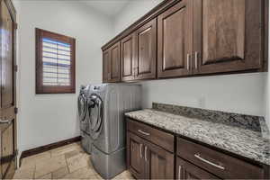 Laundry room with cabinet space, stone tile flooring, and independent washer and dryer
