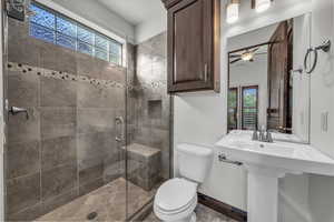 Bathroom featuring a shower stall and ceiling fan