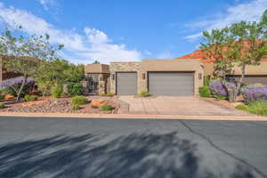 Adobe home with stone siding, stucco siding, driveway, and an attached garage