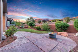 Patio terrace at dusk with a patio area, a fenced backyard, and an outdoor fire pit