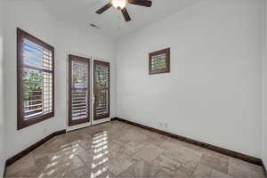 Empty room with stone tile floors and a ceiling fan
