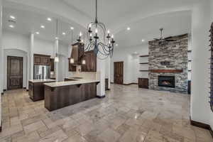 Kitchen with open floor plan, hanging light fixtures, dark brown cabinetry, a peninsula, and arched walkways