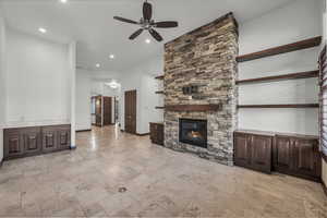Unfurnished living room featuring stone tile flooring, ceiling fan, a fireplace, and recessed lighting