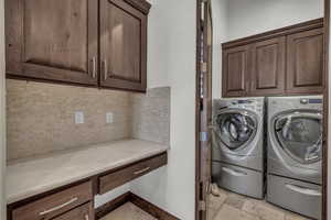 Laundry area featuring washer and dryer, stone tile floors, and cabinet space
