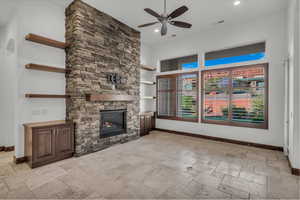 Unfurnished living room with stone tile floors, a stone fireplace, ceiling fan, recessed lighting, and built in features