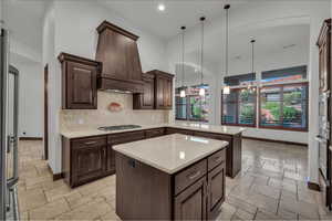 Kitchen featuring stone tile flooring, decorative light fixtures, a kitchen island, tasteful backsplash, and recessed lighting