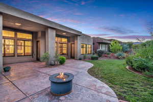 Patio terrace at dusk with an outdoor fire pit, a patio area, and a lawn
