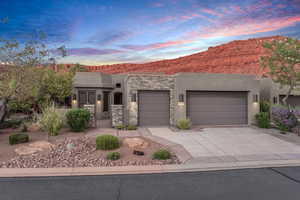 View of front of house featuring stucco siding, concrete driveway, a garage, a mountain view, and stone siding