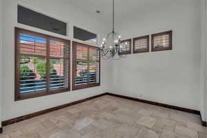 Unfurnished dining area with stone tile floors and a chandelier
