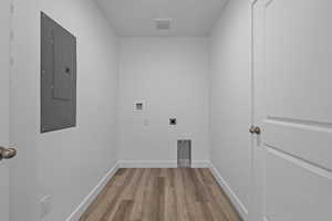 Washroom with light wood-style floors, electric panel, washer hookup, and hookup for an electric dryer